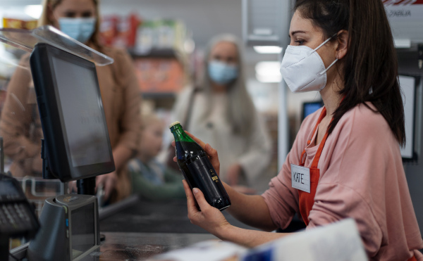 A checkout counter cashier scans bottle in supermarket.