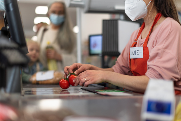 Checkout counter cashier scans vegetable in supermarket.