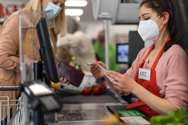 A checkout counter cashier looking to pay slip after coustomer's complaint in supermarket,