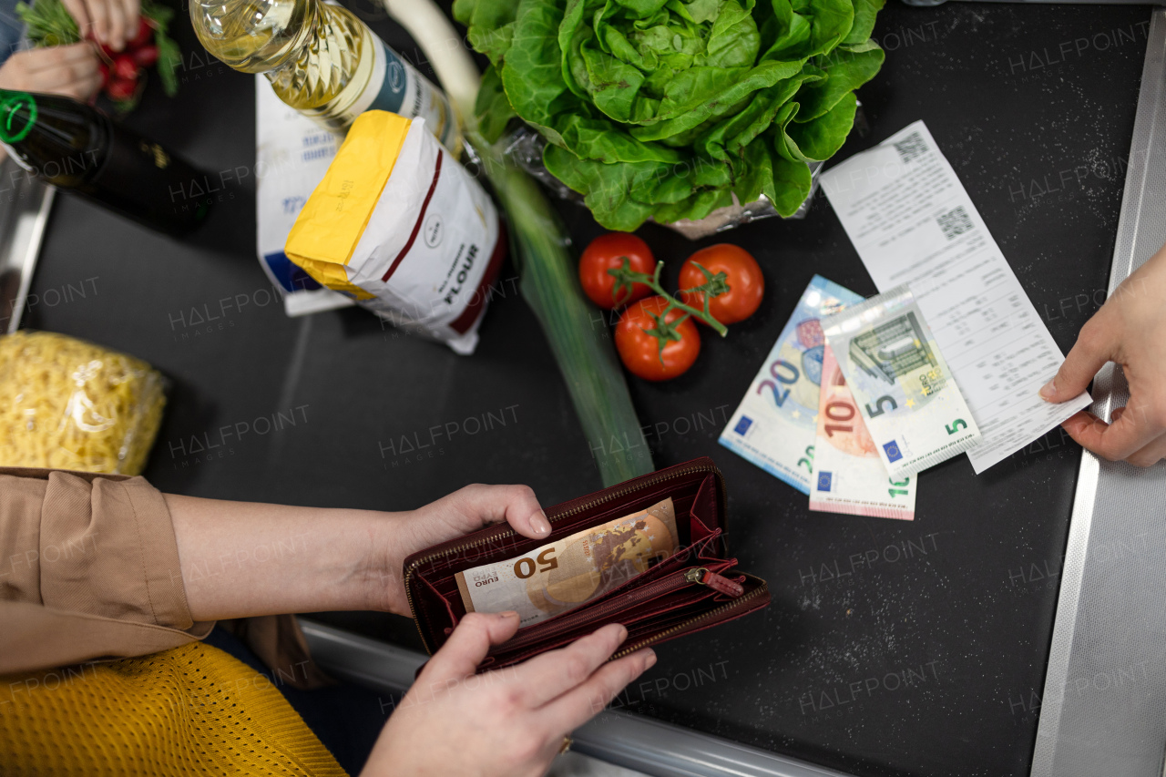 A close-up of woman giving money at the cash desk in supermarket