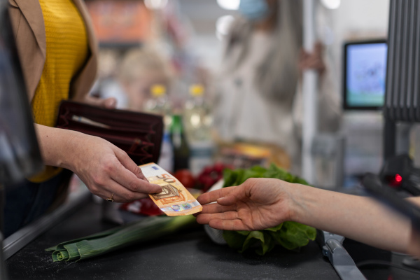 A close-up of woman giving money at the cash desk in supermarket