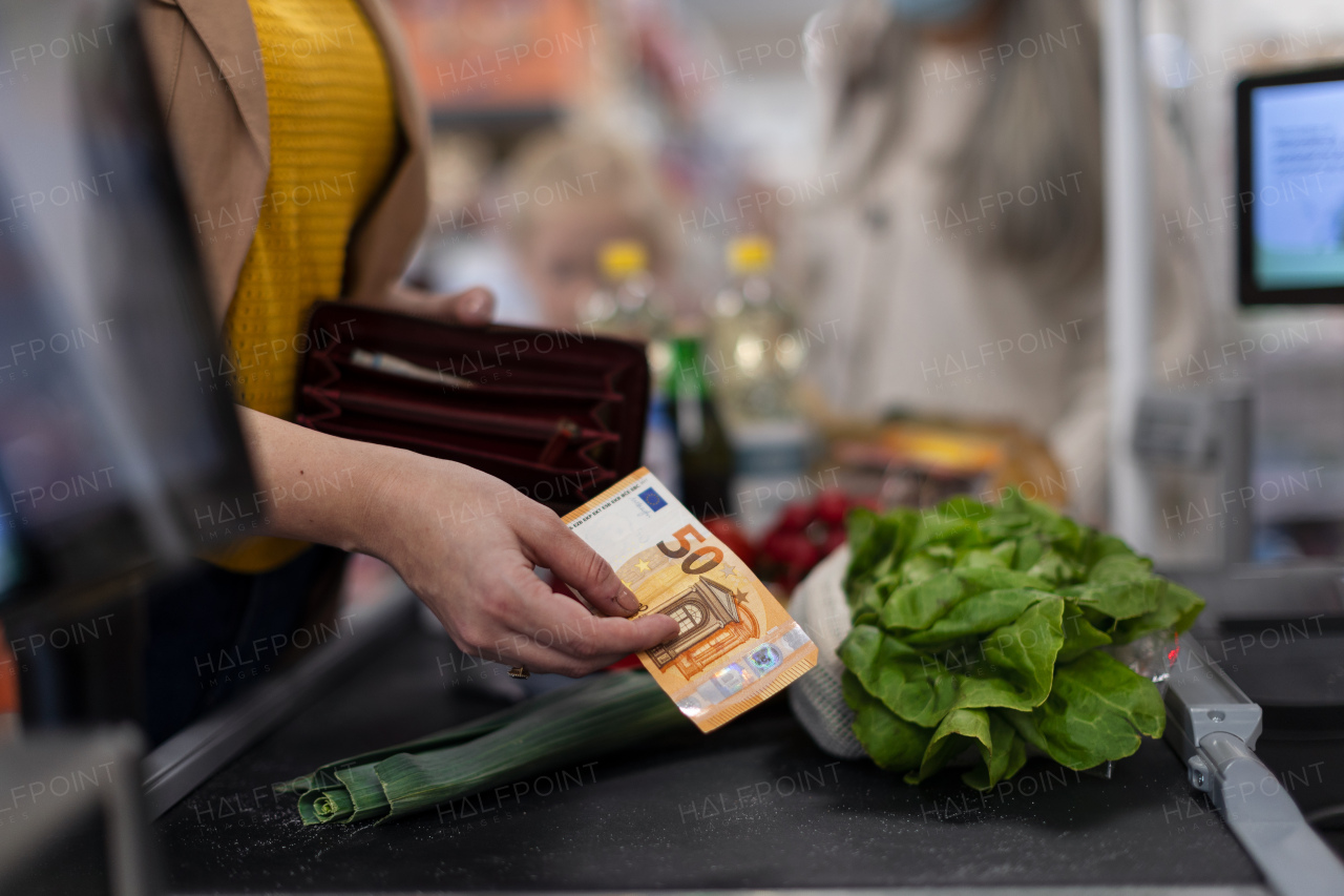 A close-up of woman giving money at the cash desk in supermarket