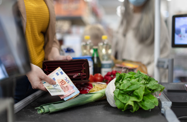 A close-up of woman giving money at the cash desk in supermarket