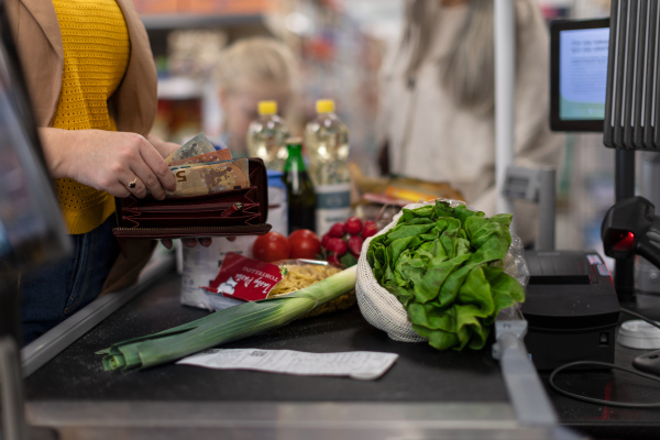 A close-up of woman giving money at the cash desk in supermarket