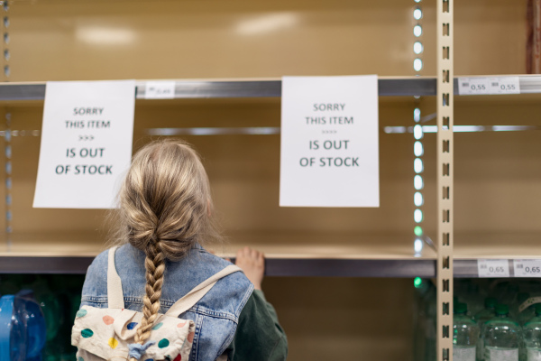 A little girl shopping and looking to empty shelves in a grocery store