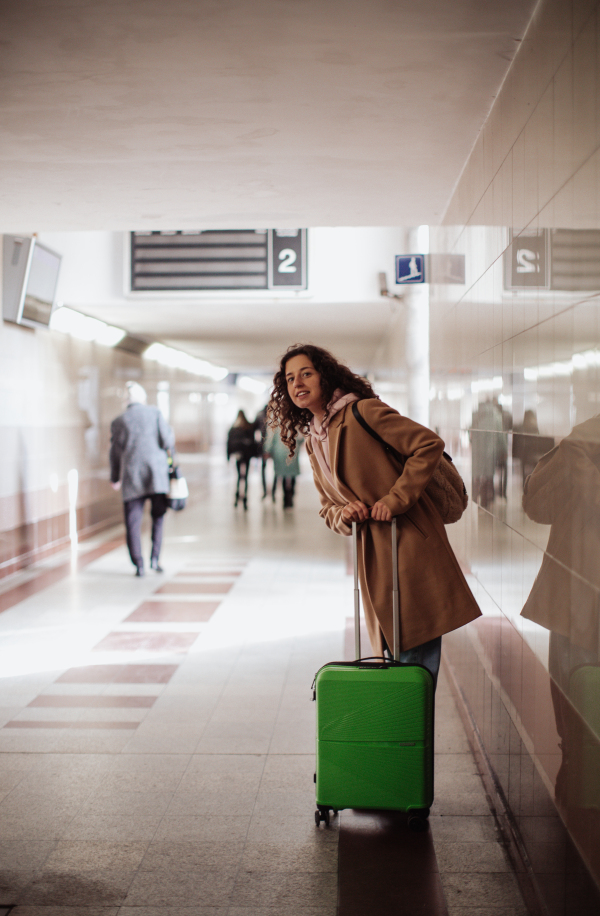 A woman traveler tourist with luggage standing in station and waiting somebody.