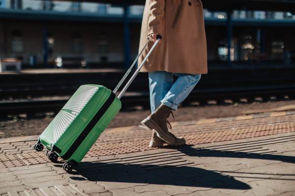 A woman traveler tourist waiting with luggage at train station, cut out.