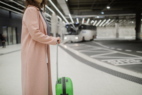 A woman traveler tourist waiting with luggage at bus station, cut out.