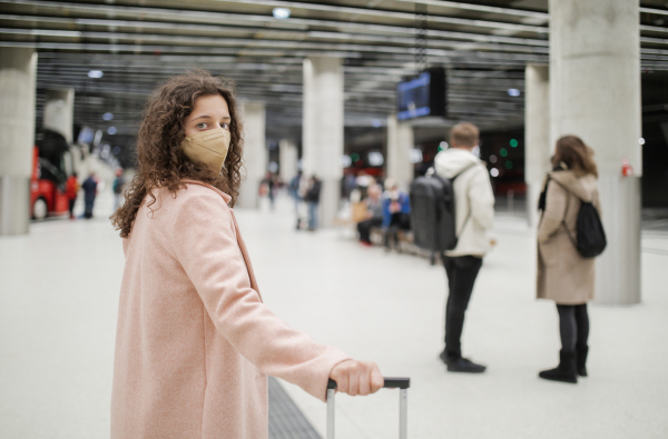 Alone woman traveler waiting with luggage at bus station, cut out.