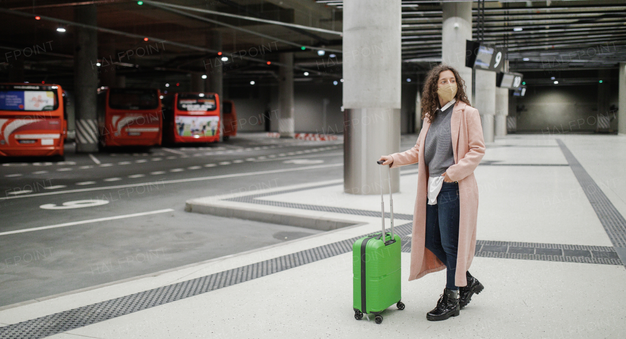 Alone woman traveler waiting with luggage at bus station, cut out.