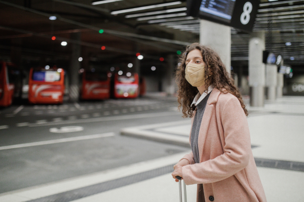 Alone woman traveler waiting with luggage at bus station, cut out.