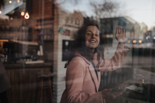 A young woman drinking tea and looking out of the cafe window while enjoying her leisure time alone