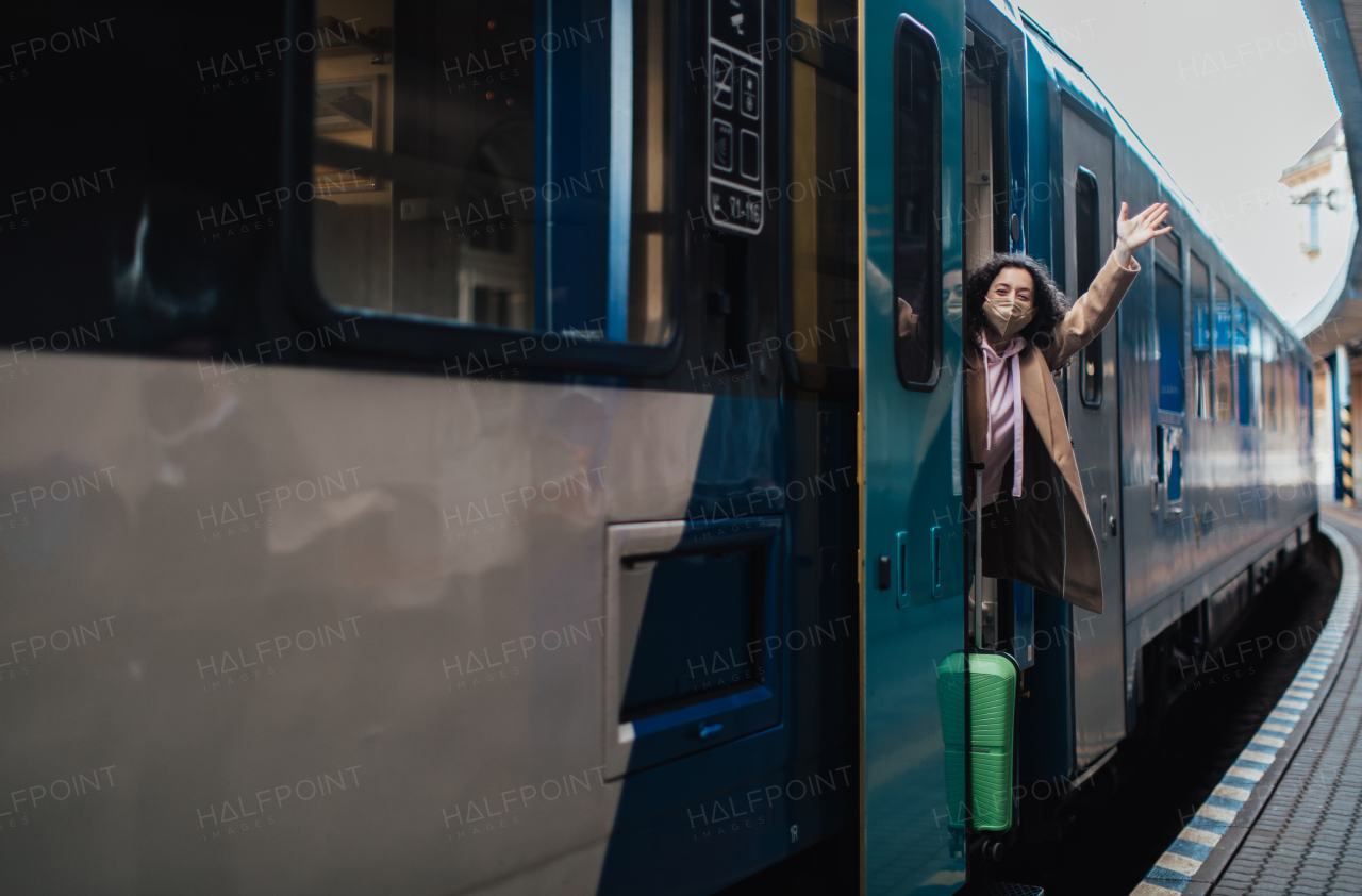 A happy young traveler woman with luggage getting off the train at train station platform