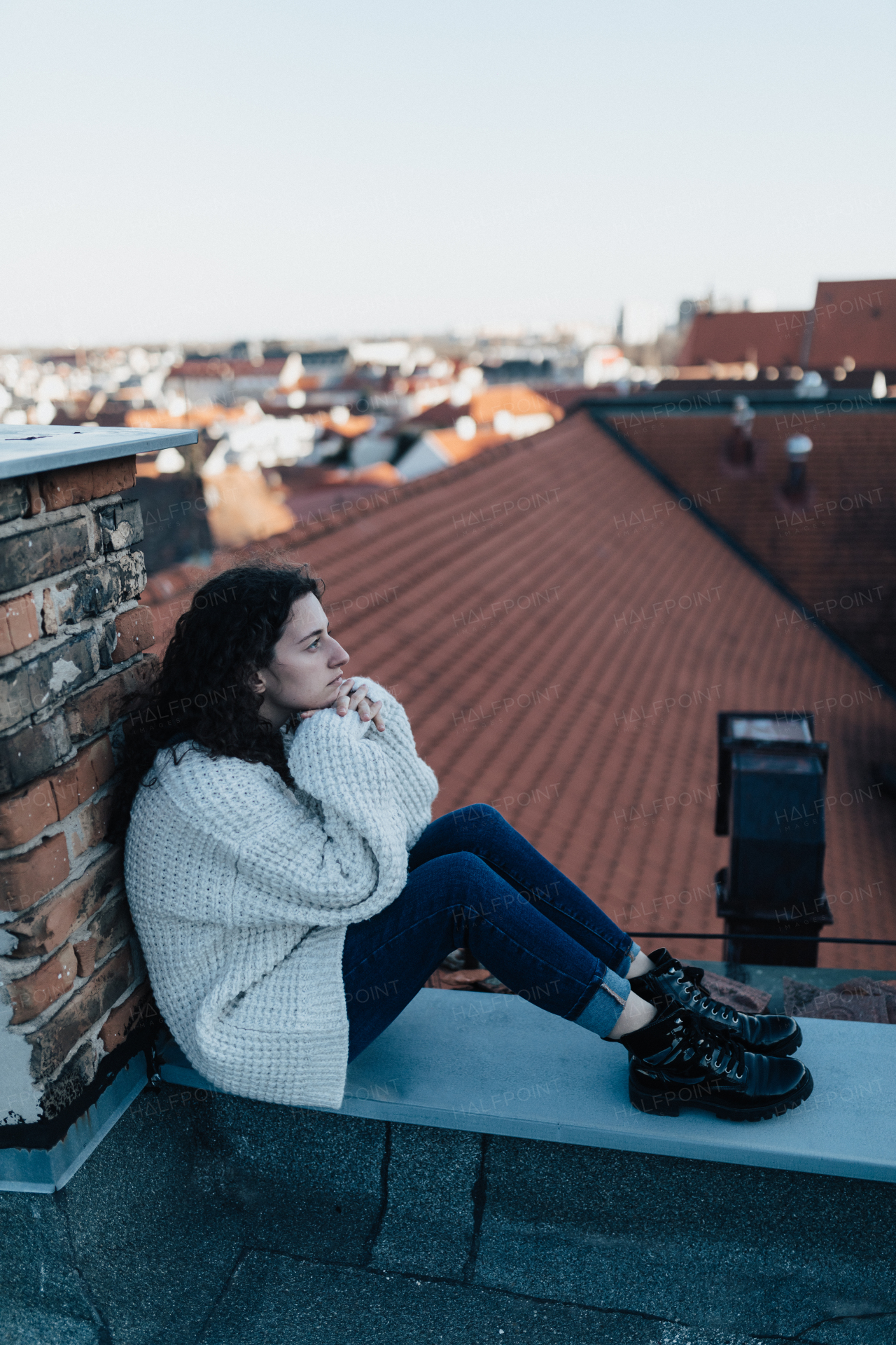 An unhappy young woman resting and sitting on the roof with city view.