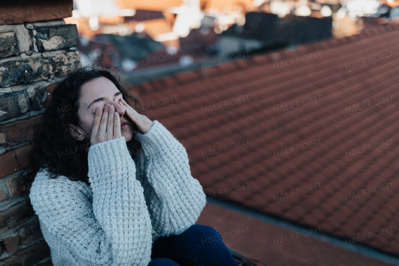 An unhappy young woman resting and sitting on the roof with city view.