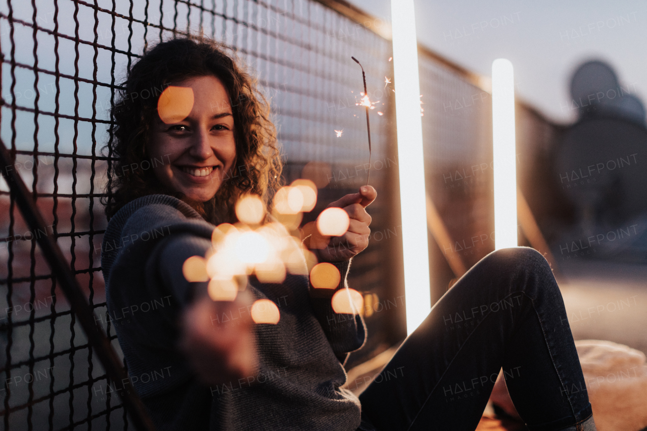 A young woman with sparklers having fun at rooftop in the city, close up.