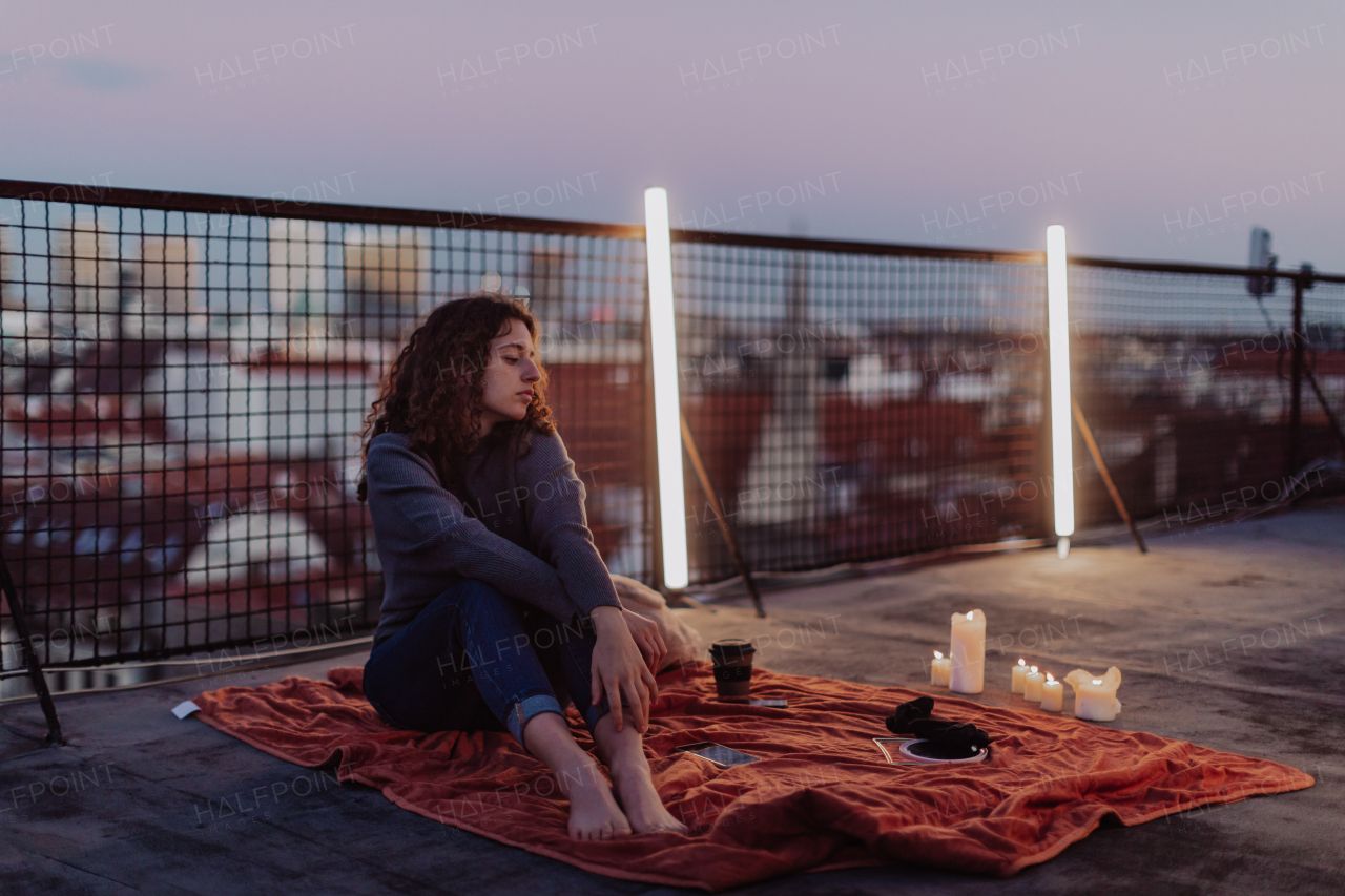 An unhappy young woman resting and sitting on the roof with city view.