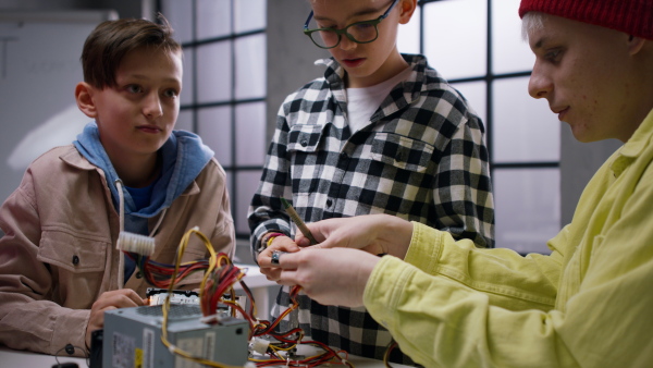 A group of happy kids with their science teacher with electric toys and robots at robotics classroom