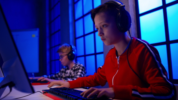 Young gamer boys with headphones playing a computer video game.