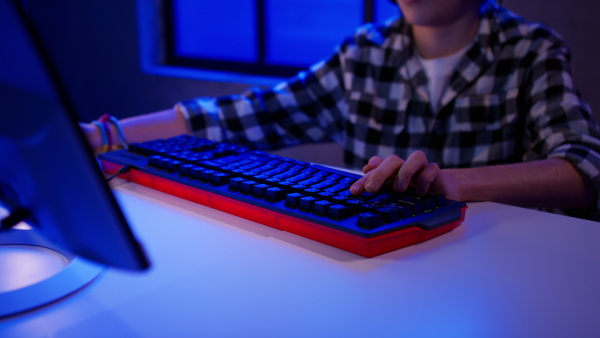 A young gamer boy with headphones playing computer video game.