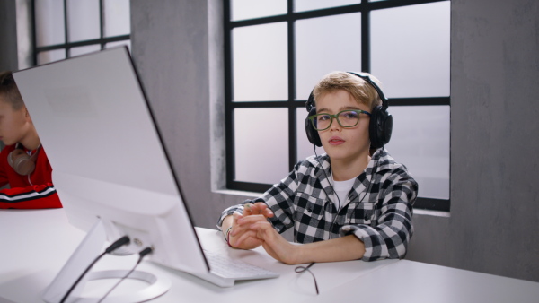 A schoolboy using computer in classroom at school