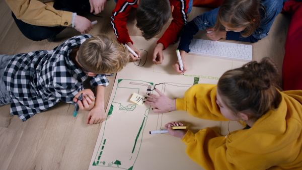 A group of happy kids with their teacher working on project together at classroom.