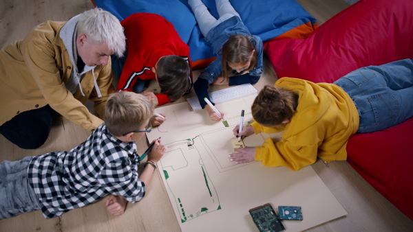 A group of happy kids with their teacher working on project together at classroom.