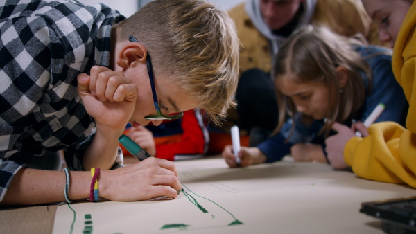 A group of happy kids with their teacher working on project together at classroom.