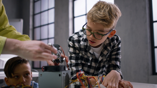 A group of happy kids with their science teacher with electric toys and robots at robotics classroom