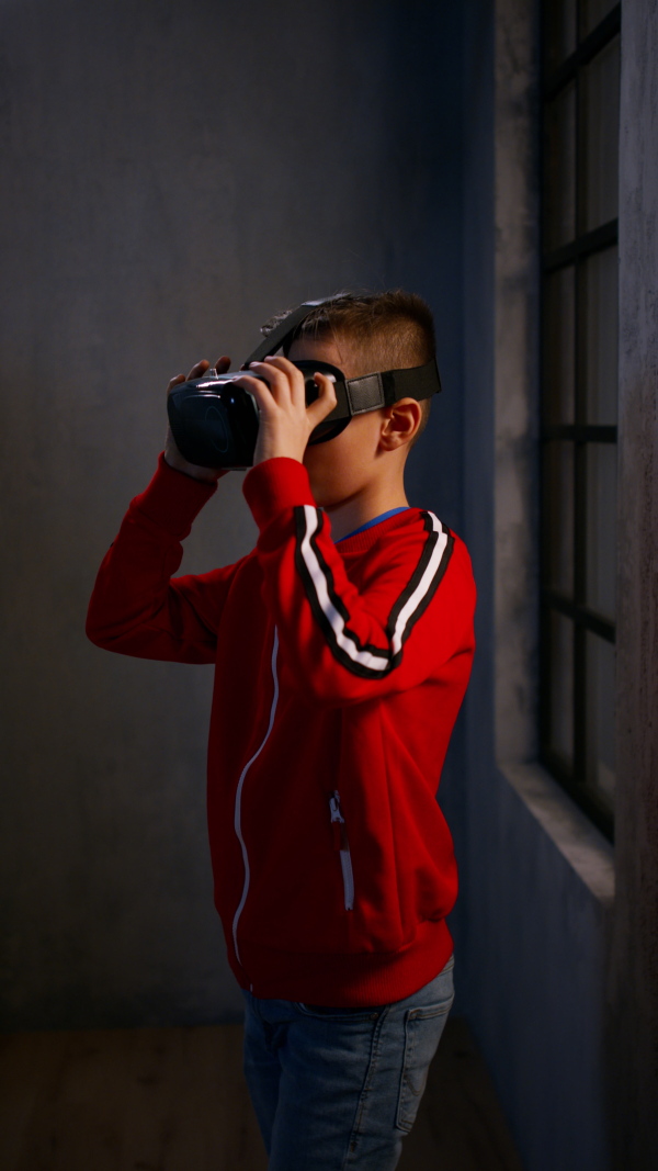 A vertical footage of schoolboy wearing virtual reality goggles at school in computer science class