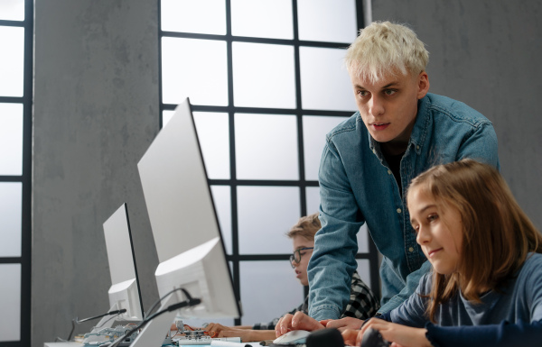 School kids with help of a teacher using computer in classroom at school