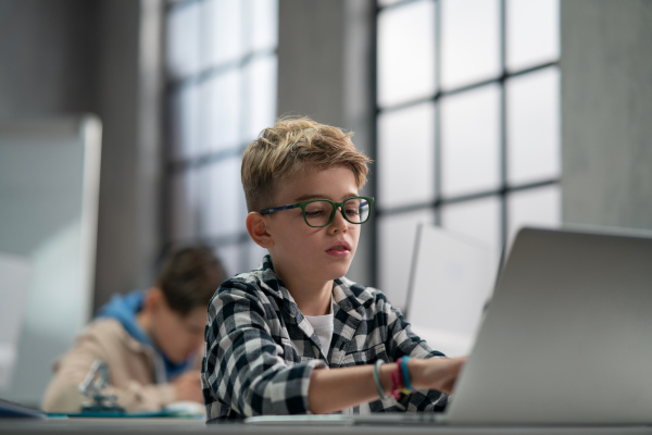 A schoolboy using computer in classroom at school