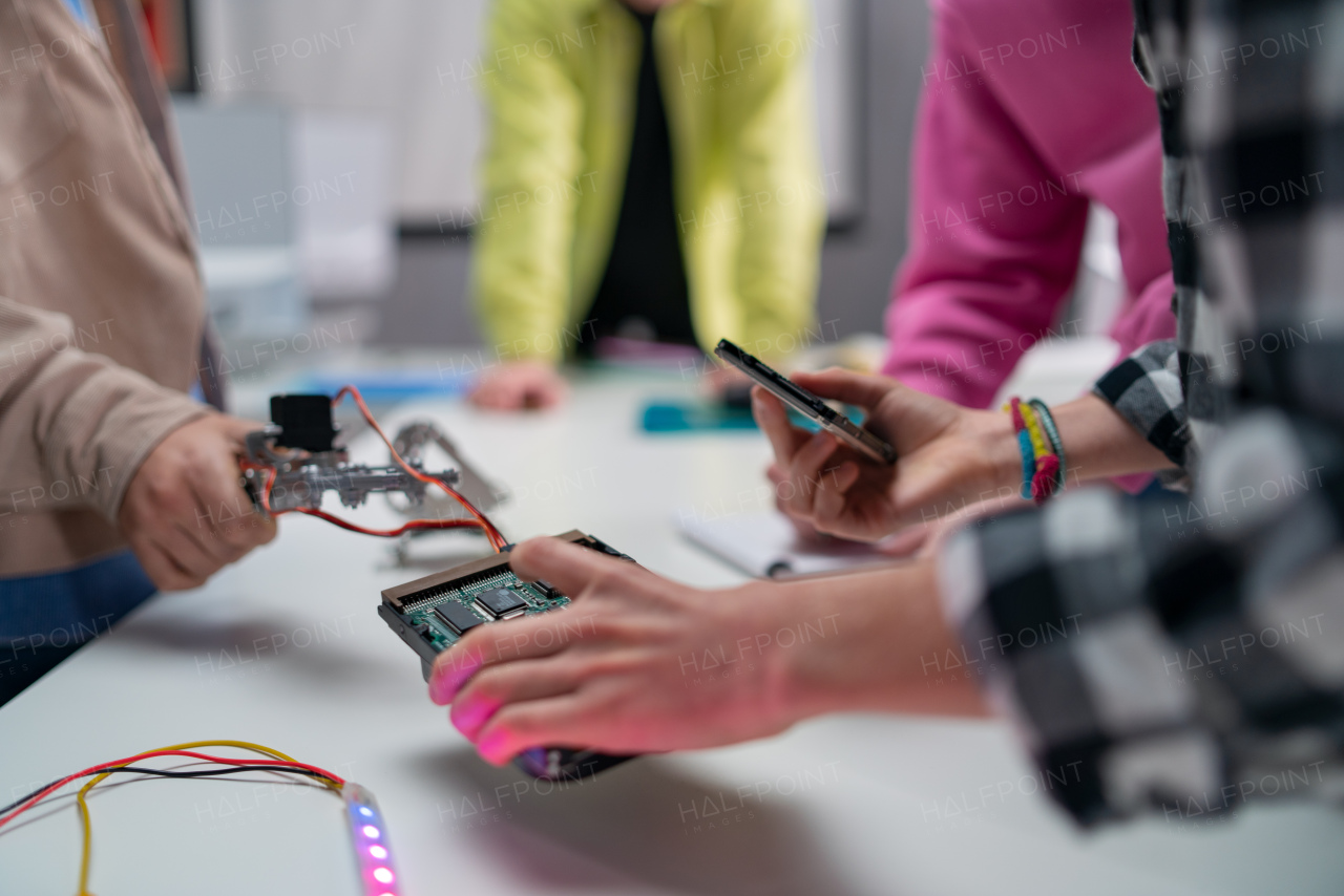 Kids with a teacher working together on project with electric toys and robots at robotics classroom, close-up