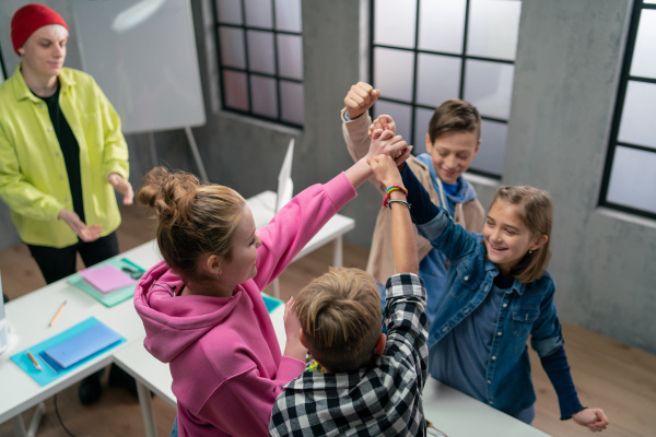 A group of happy kids with their science teacher with electric toys and robots at robotics classroom