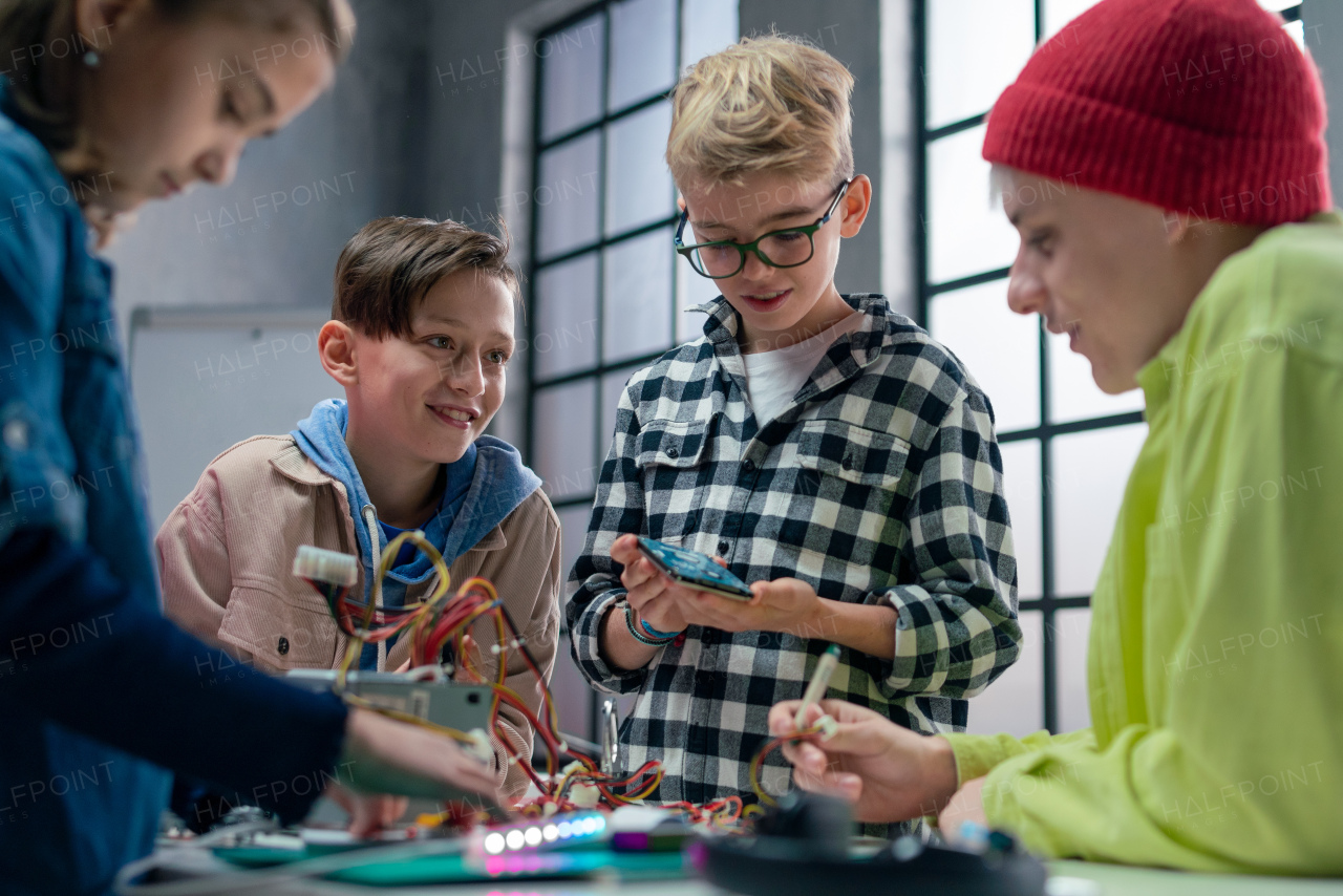 A group of happy kids with their science teacher with electric toys and robots at robotics classroom