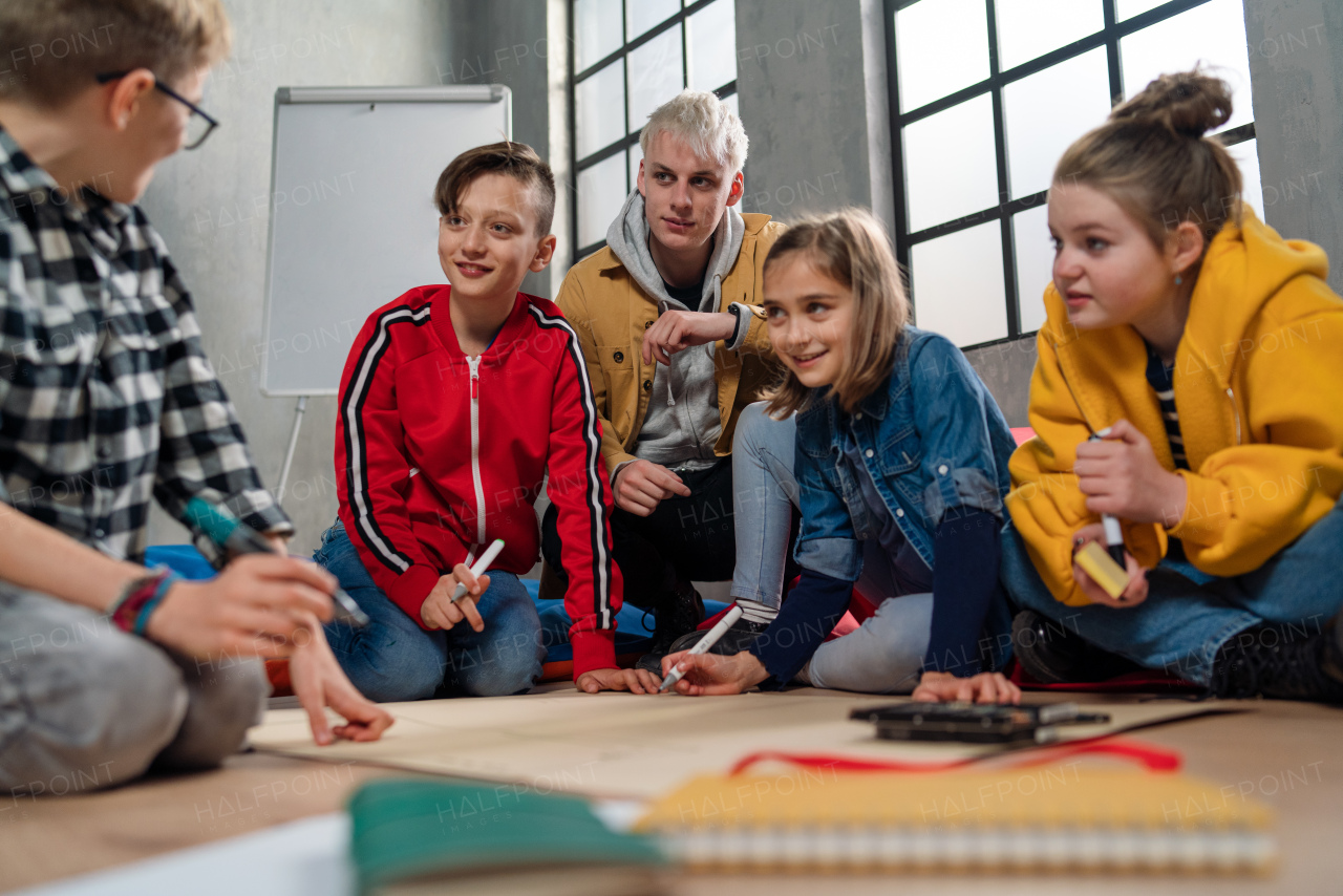 A group of happy kids with their teacher working on project together at classroom.