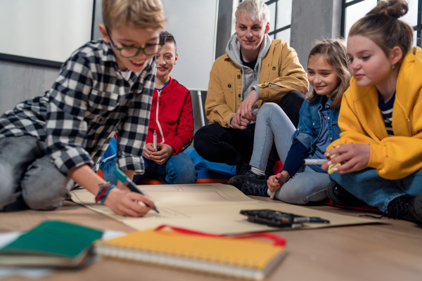 A group of happy kids with their teacher working on project together at classroom.