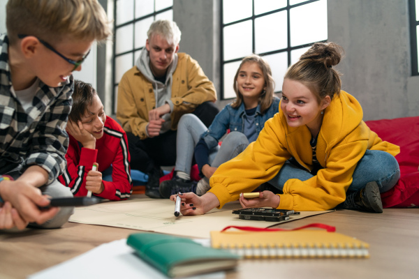 A group of happy kids with their teacher working on project together at classroom.