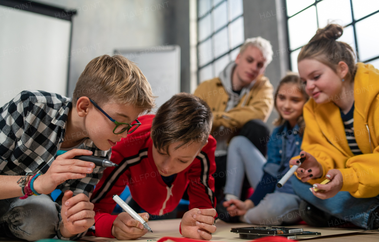 A group of happy kids with their teacher working on project together at classroom.