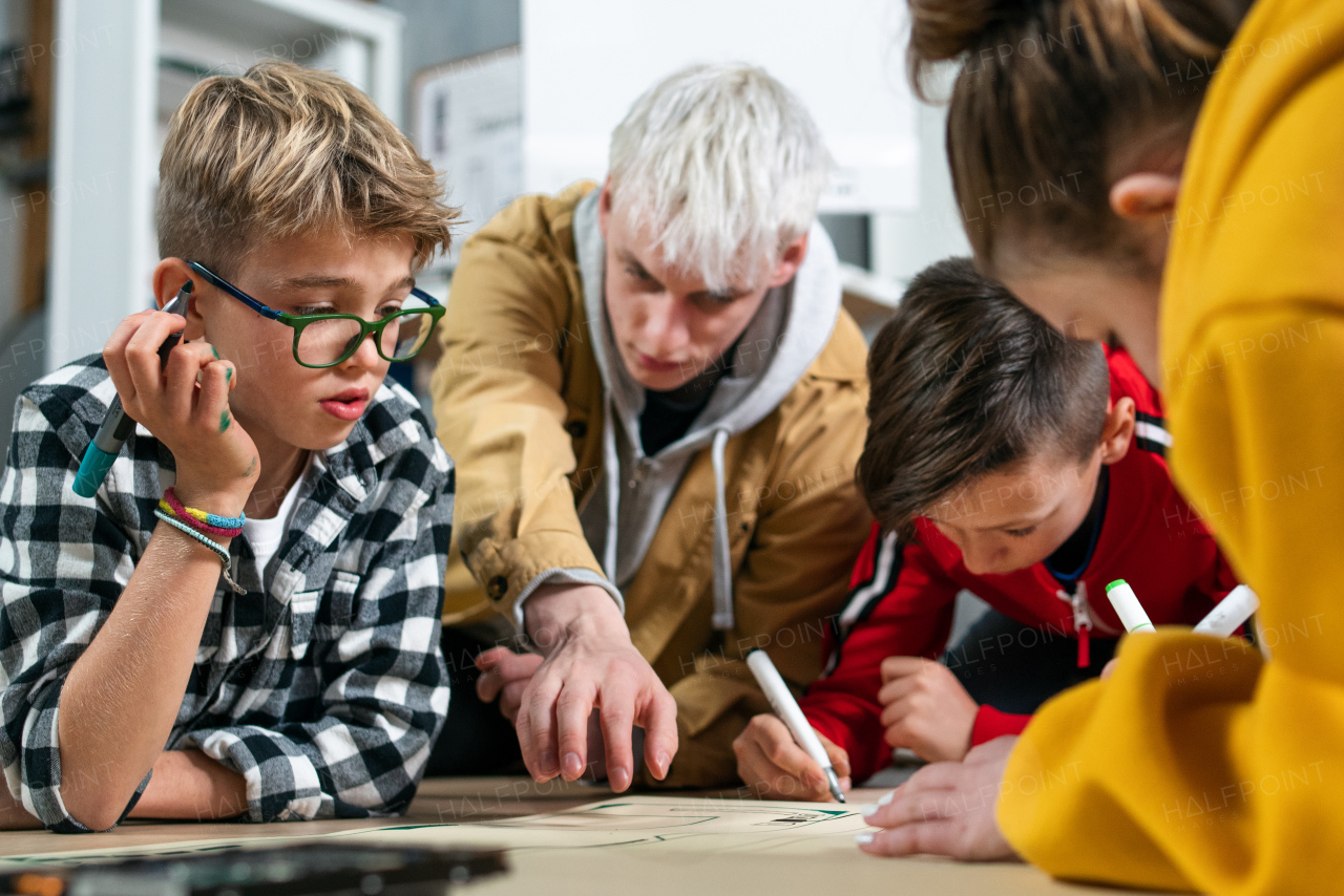 A group of happy kids with their teacher working on project together at classroom.