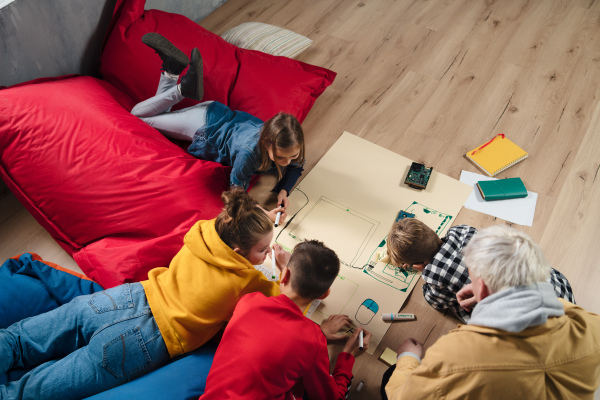 A high angle view of group of kids with their teacher working on IT project together at classroom.