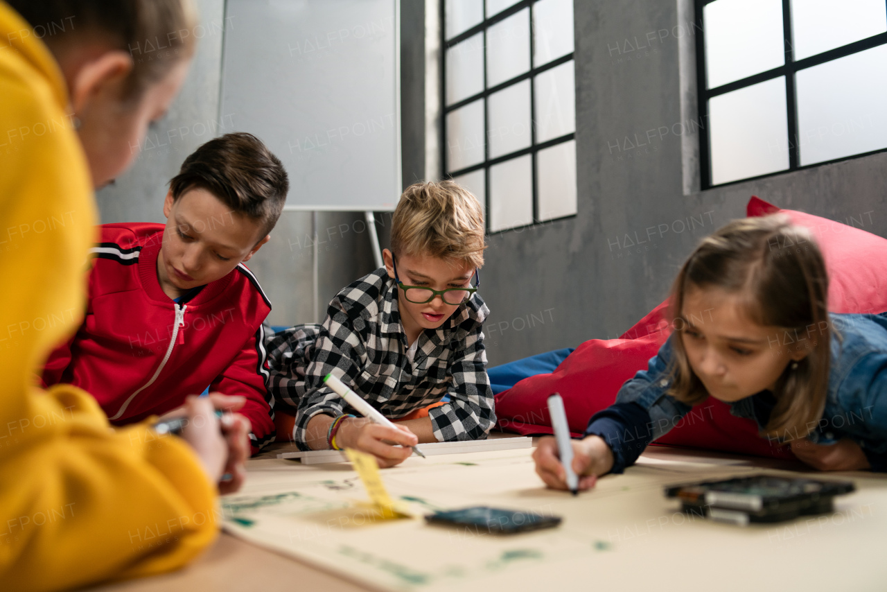 A group of happy kids with their teacher working on project together at classroom.