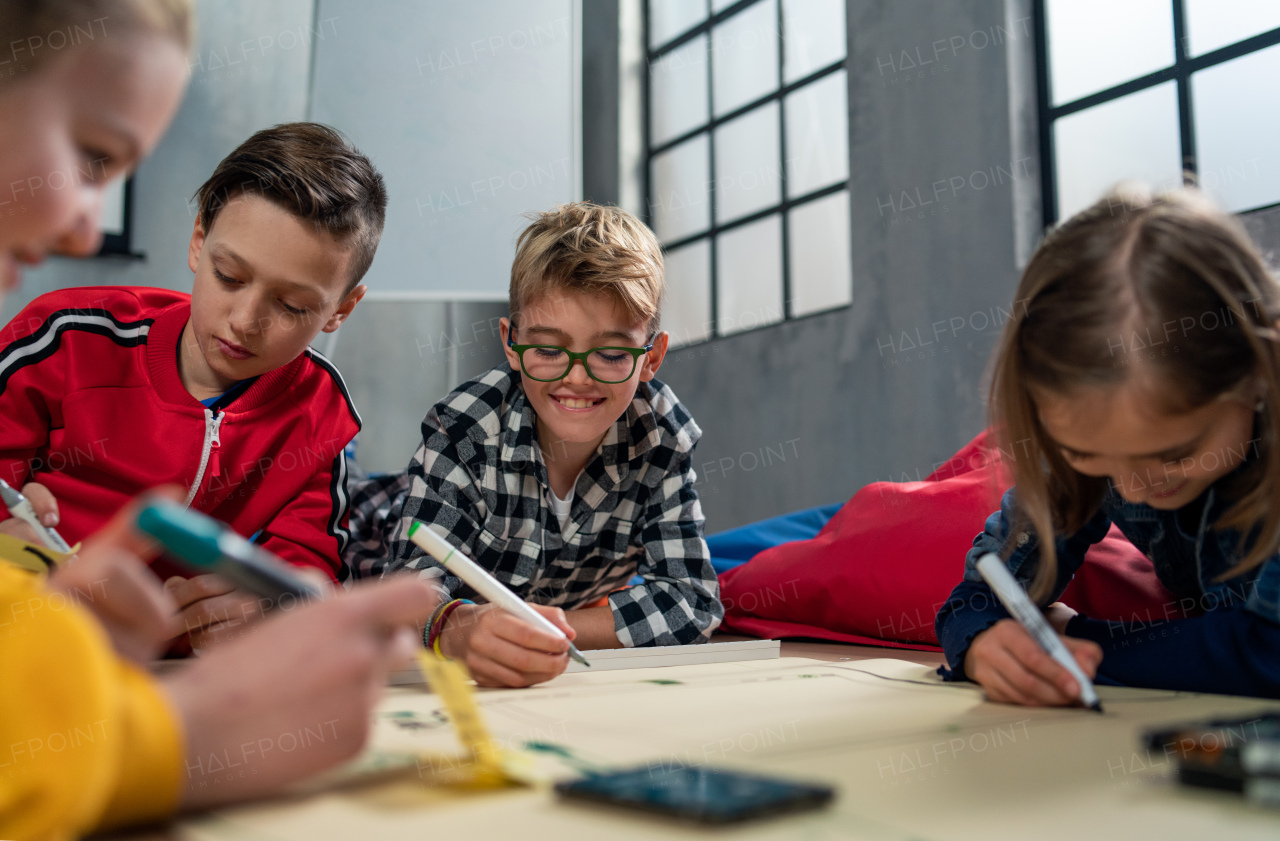 A group of happy kids with their teacher working on project together at classroom.