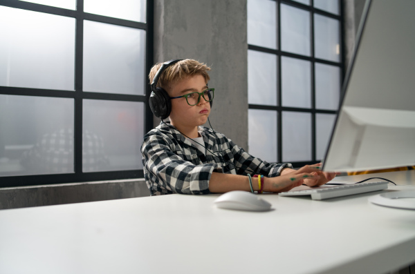 A schoolboy using computer in classroom at school