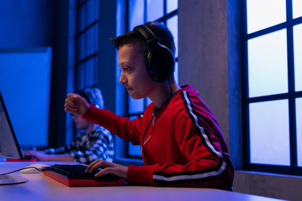 Young gamer boy with headphones playing a computer video game.