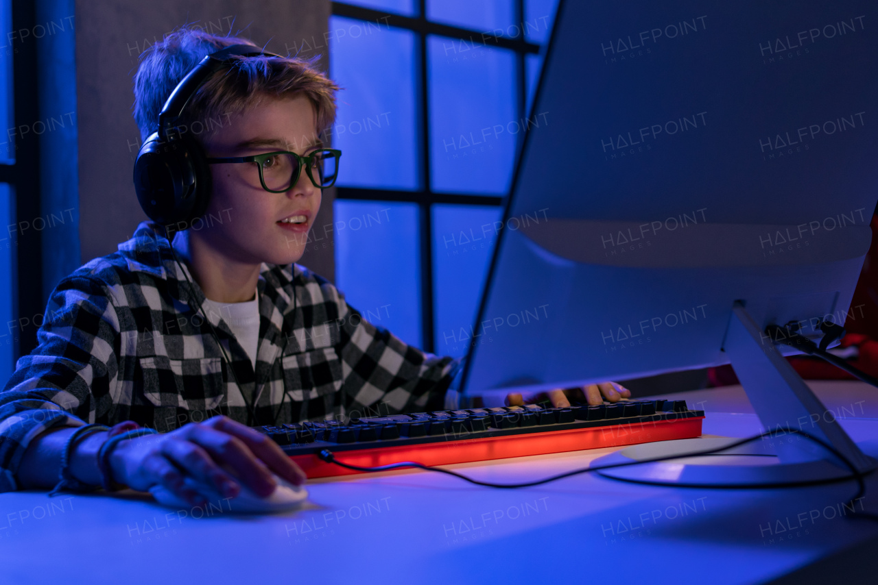 A young gamer boy with headphones playing computer video game.