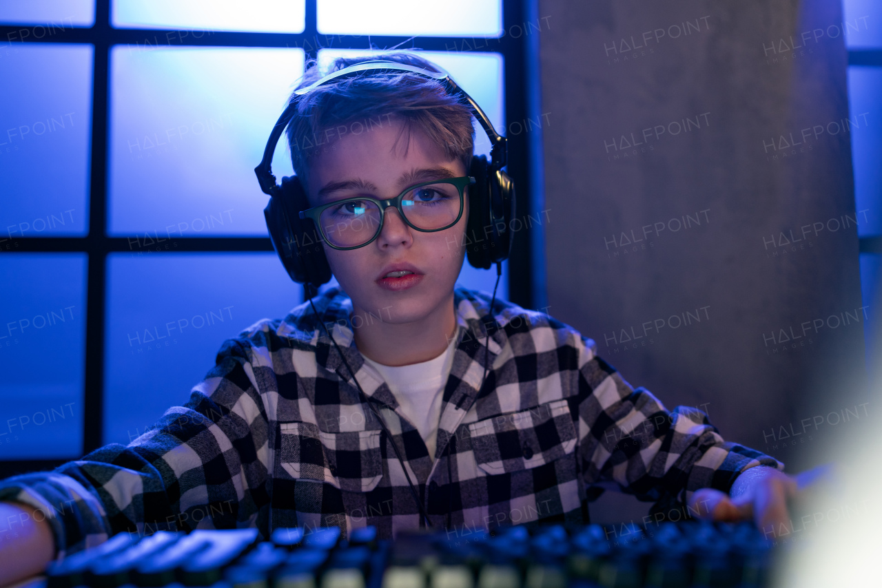 A young gamer boy with headphones playing computer video game.