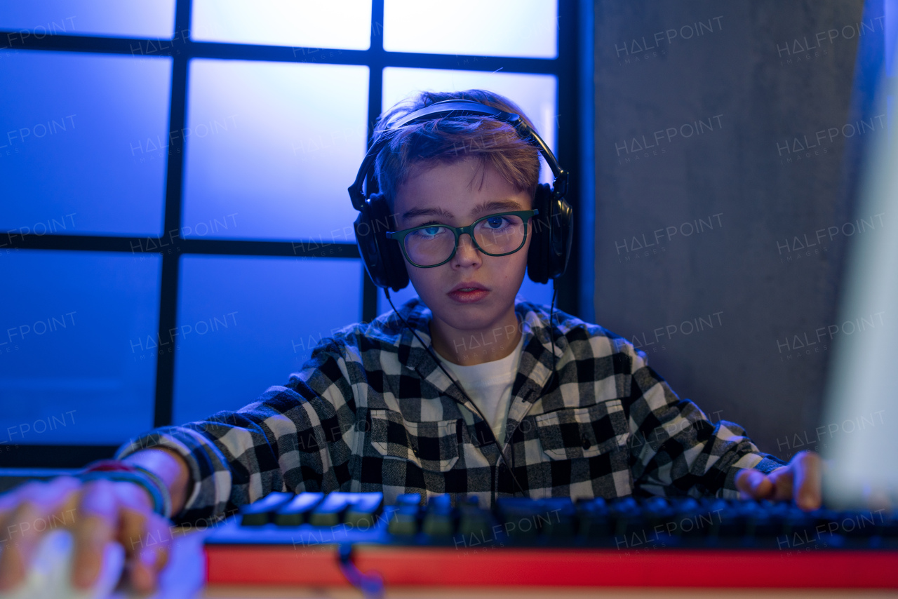 A young gamer boy with headphones playing computer video game.