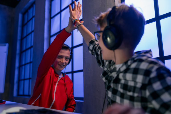 cheerfull gamer boys with headphones playing a computer video game.