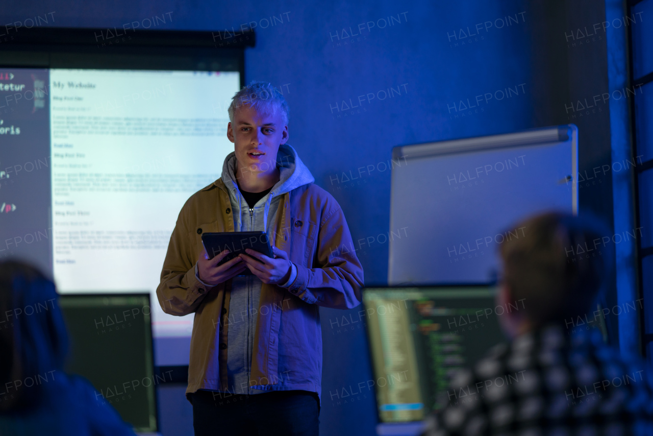 A teacher giving computer science lecture to young students in dark room. Room. Explaining Information Technology.